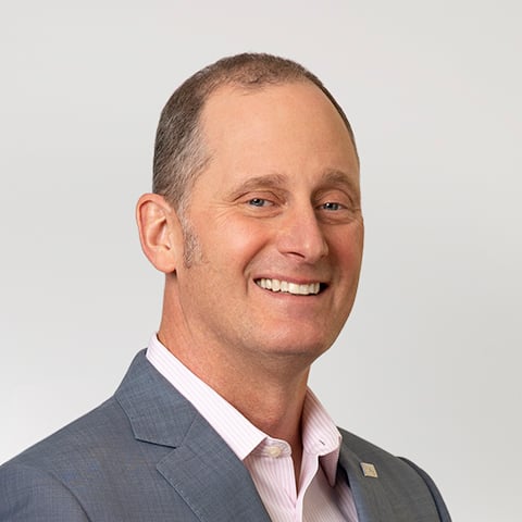 Professional headshot of Tim Byrne wearing a suit but no tie.