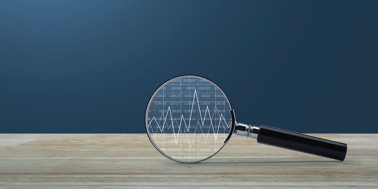 Magnifying glass leaning on a countertop with a line graph in the circular glass.