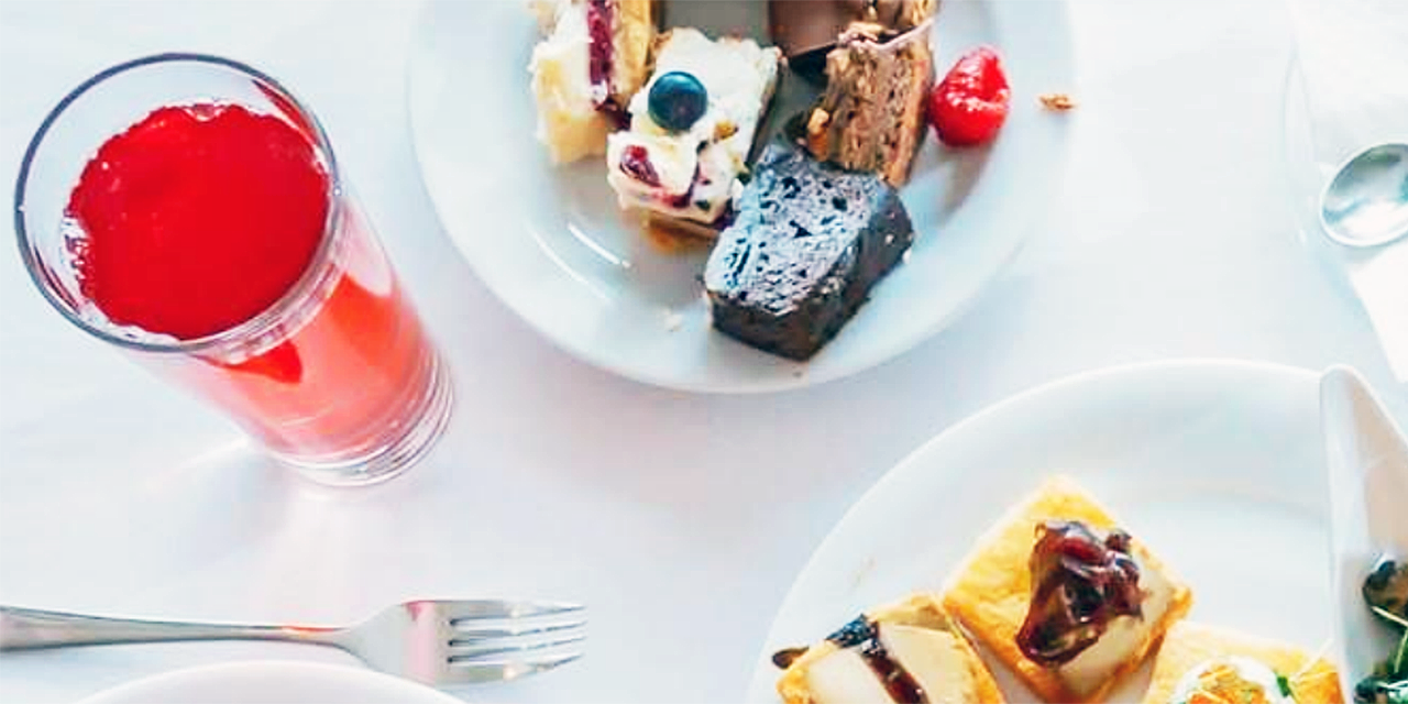 Fork, glass and plates of food on a table.